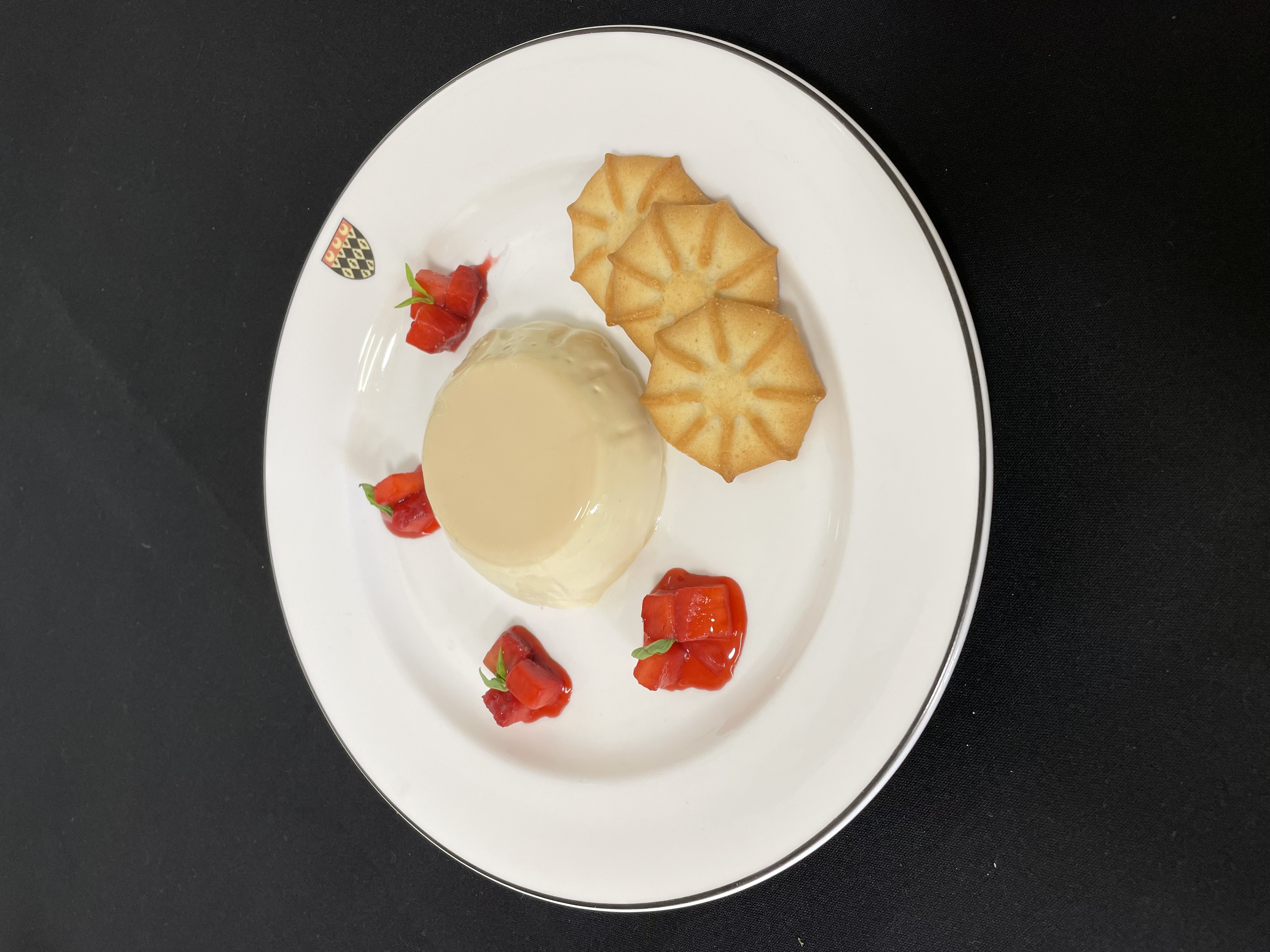 Vanilla panna cotta served with poached strawberries, shortbread and baby basil