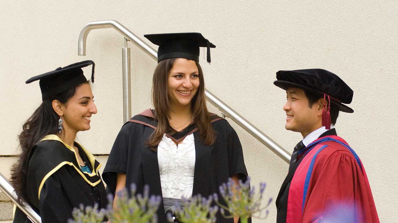 people at graduation on a staircase - fees and funding